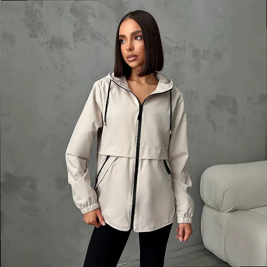 Frau in beiger Jacke mit Kapuze und schwarzem Reißverschluss