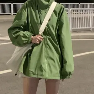 Frau in grüner Jacke mit hohem Kragen auf der Straße