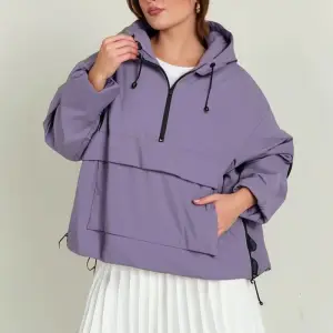 Frau in lilafarbener Schlupfjacke mit Kapuze und Halbreißverschluss