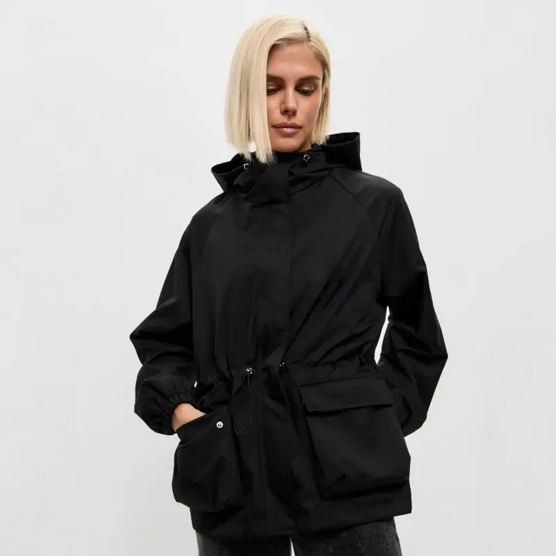 Frau in brauner Jacke mit Kordelzug und großen Taschen